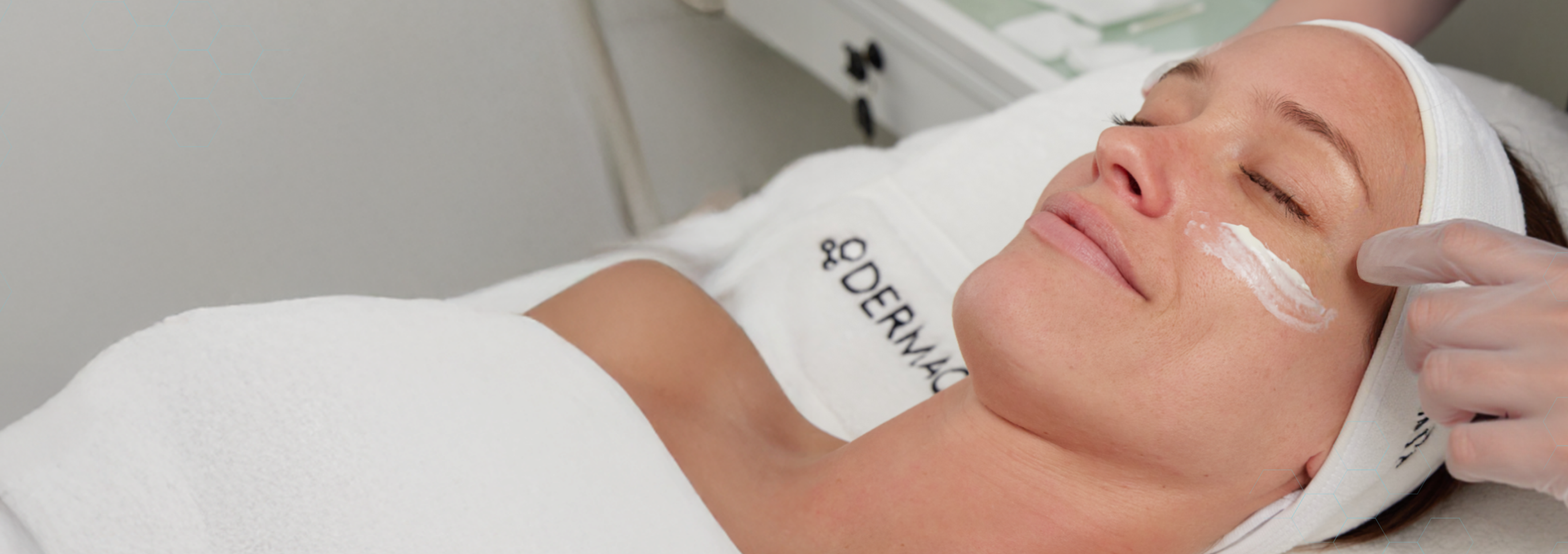 Woman receiving a facial treatment with a professional in a clinical setting.