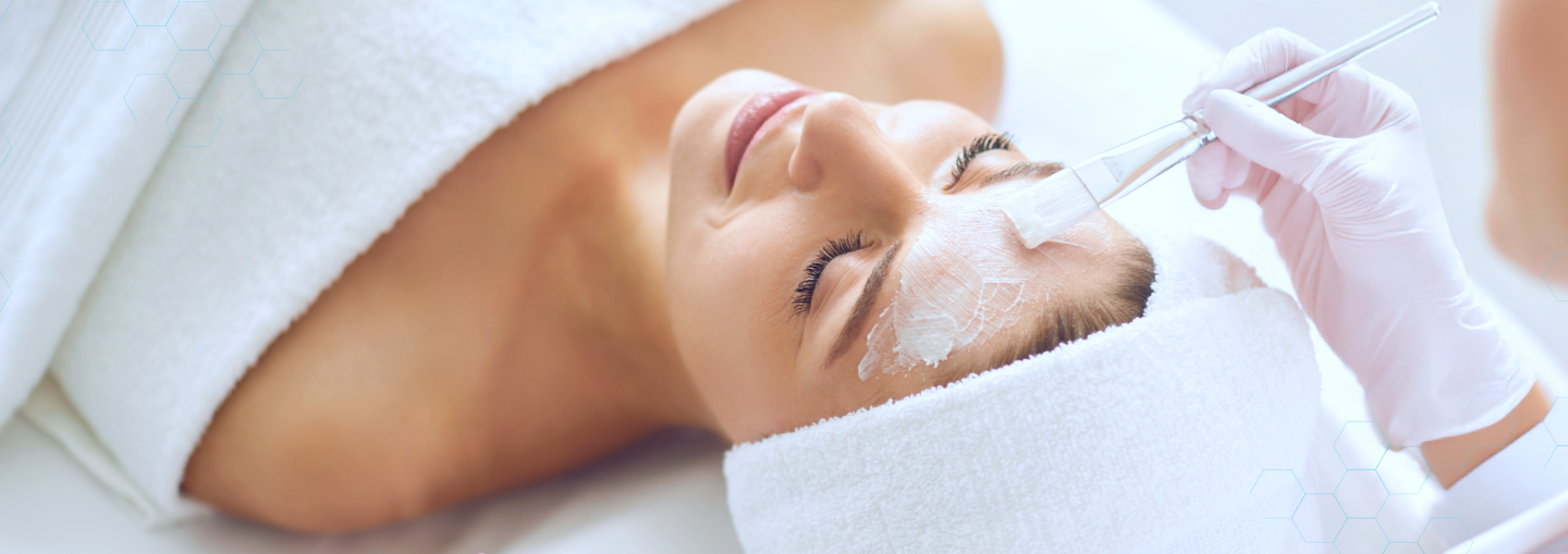 Person receiving a facial treatment with a skincare professional applying cream to their face.